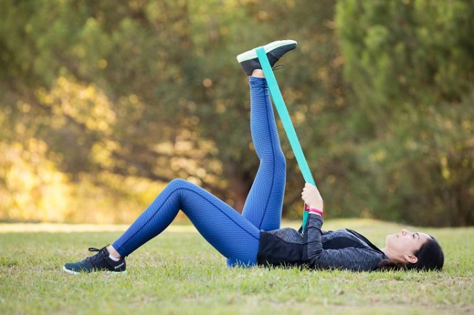 picture of a woman laying on a grass outside using feet stretchers 