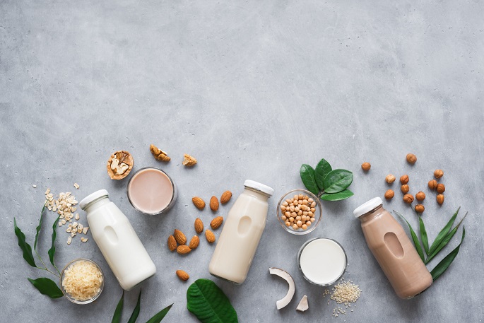 Various vegan plant based milk and ingredients, top view, copy space. Dairy free milk substitute drink, healthy eating.
