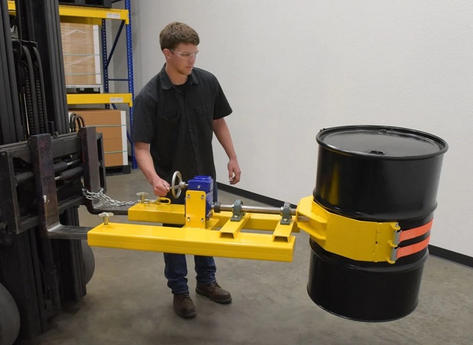 Man standing by drum handling forklift attachment with barrel